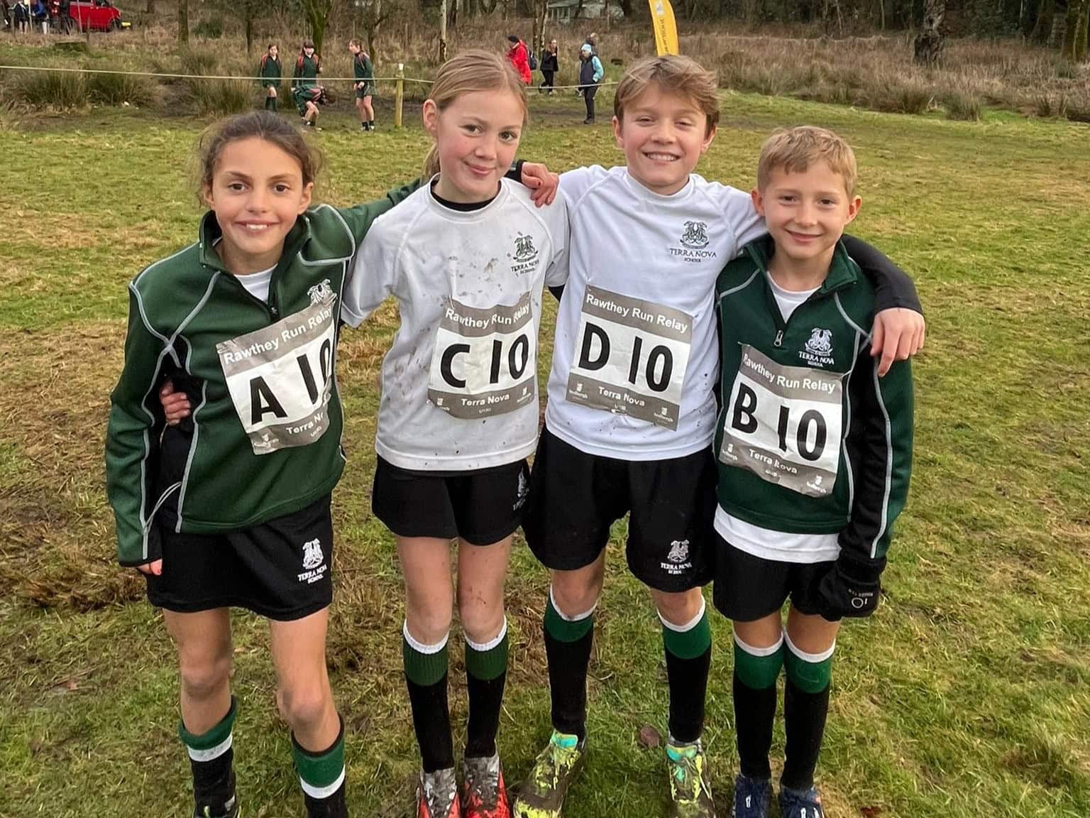 Two girls and two boys in muddy cross country gear having just finished a race.