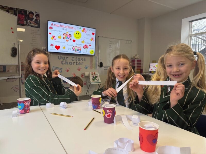 Three girls smiling and decorating cups