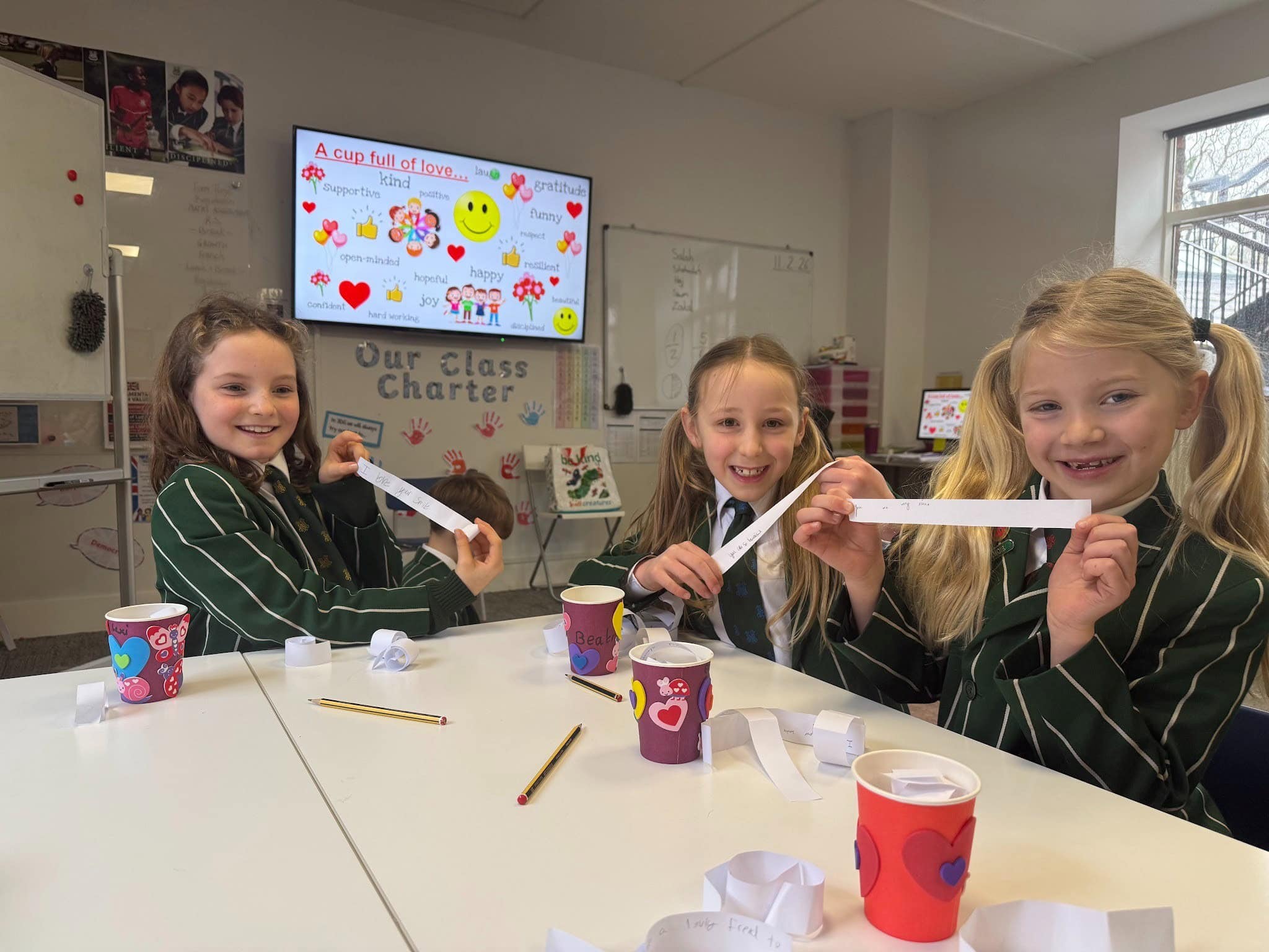 Three girls smiling and decorating cups