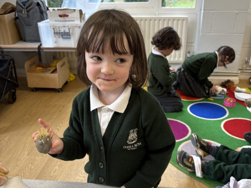 Young girl holding a clay model of a hedgehog