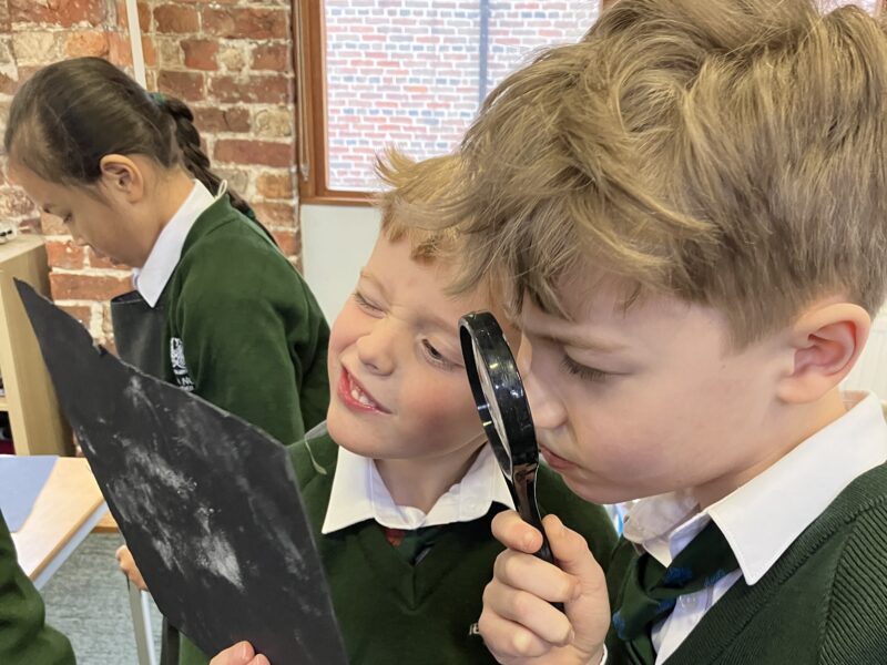 Children examining evidence with a magnifying glass.