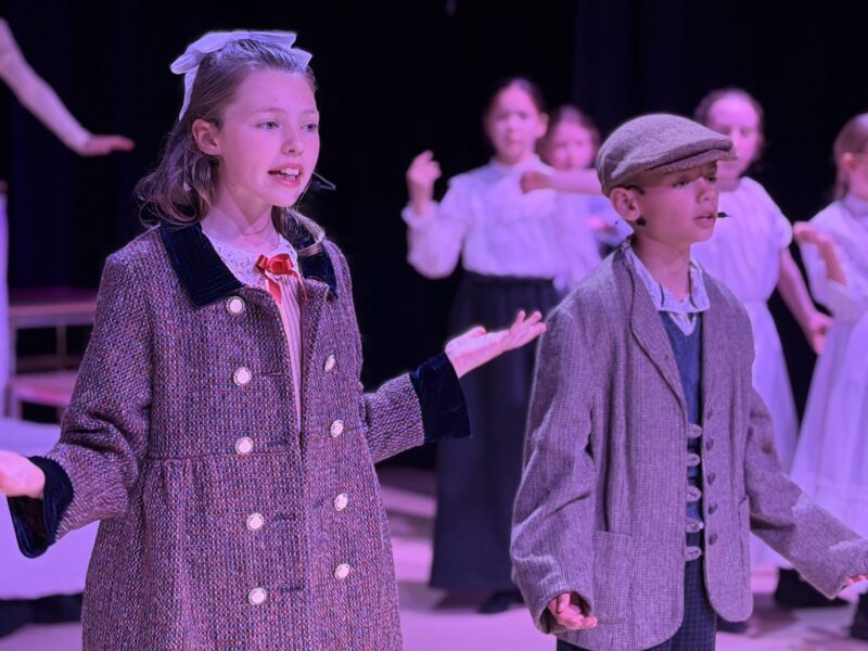 School children in Mary Poppins costumes performing on stafe